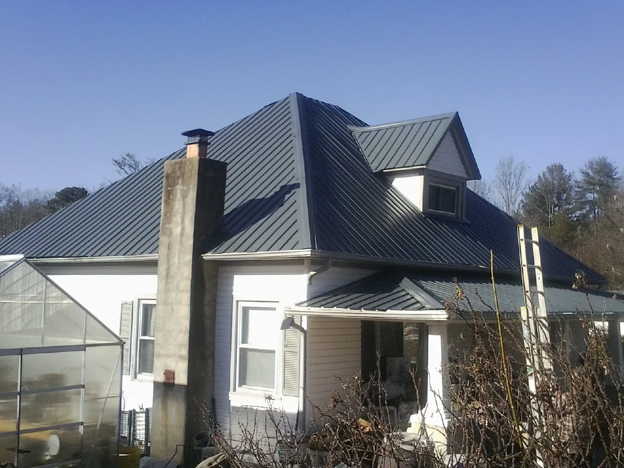 Dark blue standing seam metal roof on a white farmhouse with dormer — Slate & Tile Roof Repair by Roofing Brothers in Walterville
