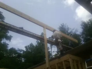 Carpenter setting a ridge beam over a new addition frame — Ice Dam Removal by Roofing Brothers in Walterville