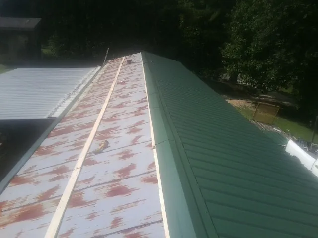 Old rusted panels beside newly installed green metal roofing — Wind Damage Roof Repair by Roofing Brothers in Walterville