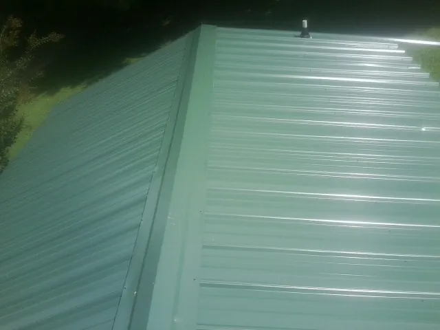 New green metal panels meeting at the ridge of a roof — Flat Roof Repair work by our crew in Walterville