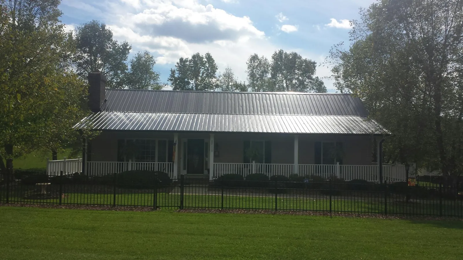 Gray metal roof on a brick ranch with a full width front porch — Gutter Guard Installation work by our crew in Walterville