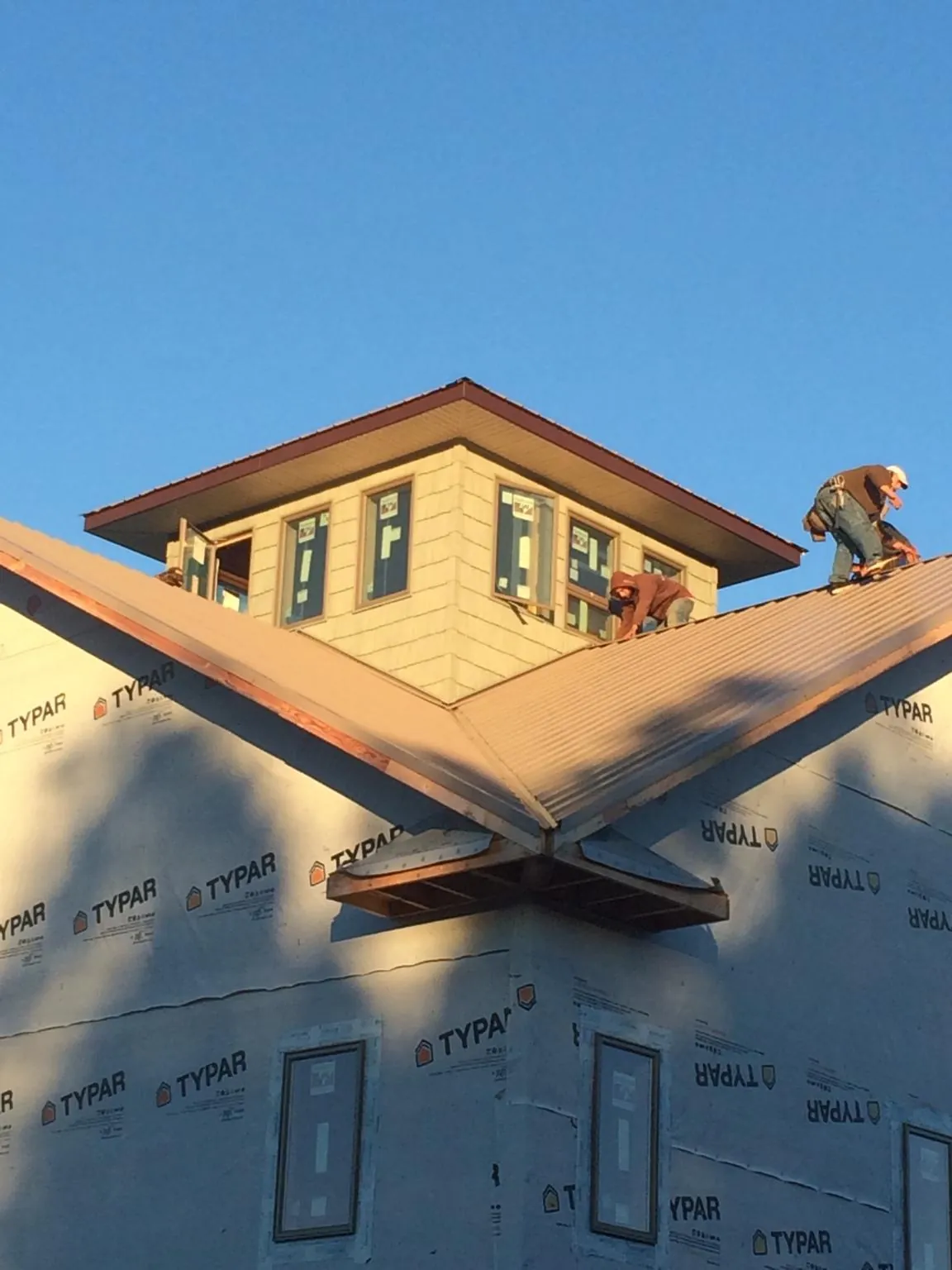 Roofers working around a rooftop cupola on a new metal roof at sunset — Roof Waterproofing in Walterville by Roofing Brothers